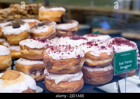 Un vassoio di ciambelle in velluto rosso in mostra per la vendita in un negozio di dolci Londra Inghilterra Regno Unito Foto Stock