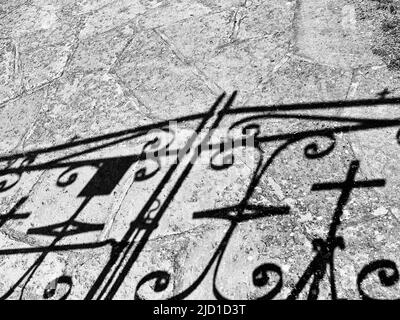 Cancello in ferro battuto con ombre a croce su un sentiero, foto in bianco e nero, Svezia Foto Stock