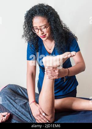 Fisioterapia della flessione del ginocchio, concetto di riabilitazione, fisioterapista con paziente Foto Stock