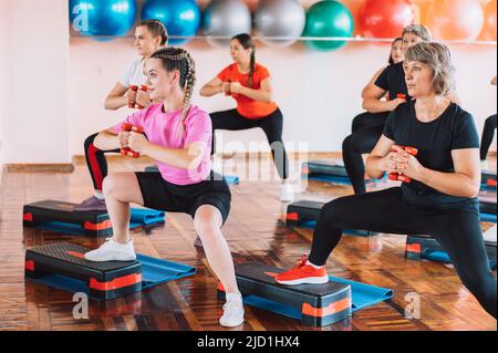 Gruppo di donne che fanno grandi squat con manubri nelle loro mani Foto Stock