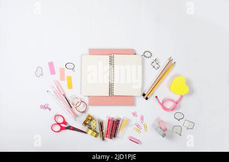 Desktop girly rosa e cancelleria con notebook vuoto. Cornice di cancelleria colorata. Concetto di ritorno a scuola. Flatlay, mock up. Foto Stock