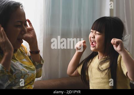 Nonna infelice che ha avuto problemi con la nonna naughty piccola rumorosa che grida. Naughty difficile ribelle bambini problemi Foto Stock