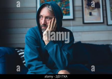 Uomo triste seduto sul divano Foto Stock