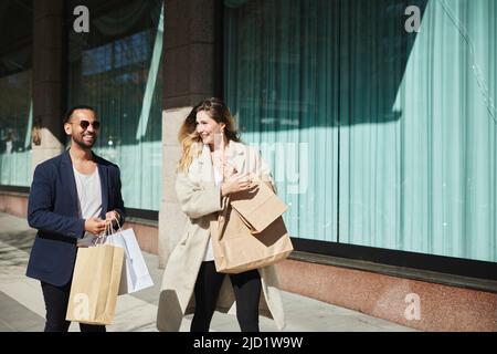 Amici che camminano lungo la strada con borse shopping Foto Stock