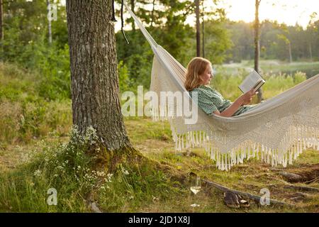 Donna che legge un libro sul amaca Foto Stock