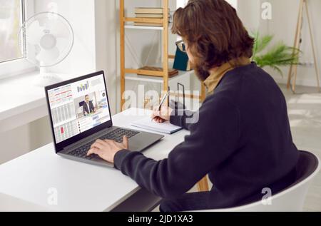 Il freelance MAN utilizza il laptop per partecipare a riunioni remote, che si trovano alla scrivania dell'ufficio domestico Foto Stock