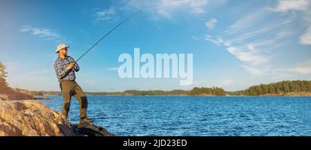 pescatore pesca dalla costa in Finlandia arcipelago marino. Spazio copia Foto Stock