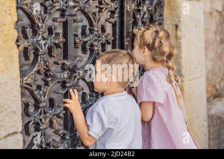 Ragazza e ragazzo che sbucciano sopra la recinzione Foto Stock