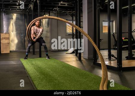 Corda magazzino fitness uomo verde erba palestra muscolare giovane, per la forza forte da attività fisica sana, muscolare persona. Croce Foto Stock