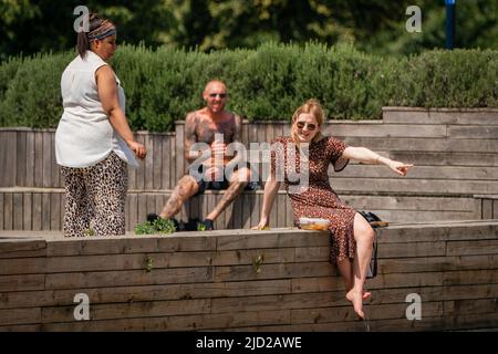 La gente gode il sole al Royal Docks, nella parte est di Londra. Secondo il Met Office, a Londra è prevista una oscilanza di 34C (93,2F) e, potenzialmente, di alcuni punti di East Anglia il venerdì. Data foto: Venerdì 17 giugno 2022. Foto Stock