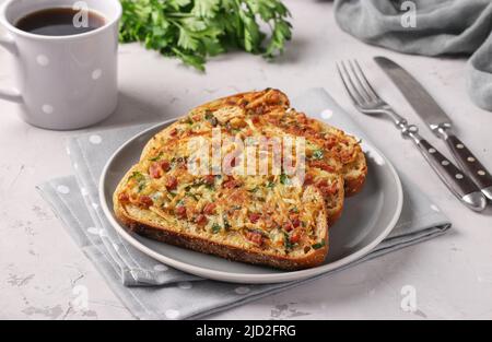 Sandwich caldi con patate e salsiccia in un piatto e una tazza di caffè su un tavolo grigio Foto Stock