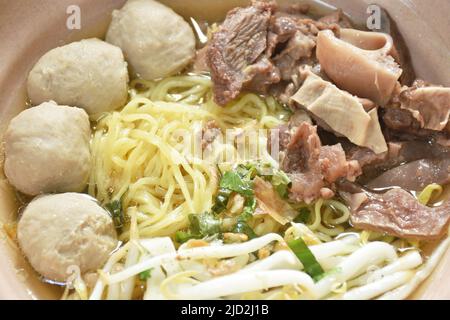 Spaghetti di uova cinesi lessati e gialli con manzo brasato e polpette di carne in zuppa sul recipiente Foto Stock