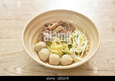 Spaghetti di uova cinesi lessati e gialli con manzo brasato e polpette di carne in zuppa sul recipiente Foto Stock