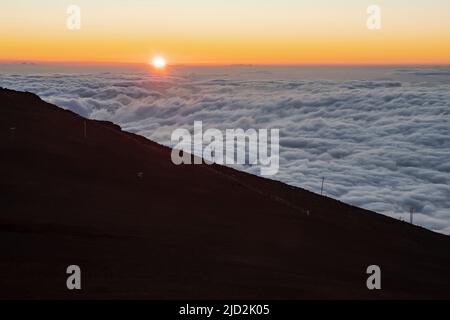 sopra le nuvole come il sole tramonta all'orizzonte sulla cima di haleakala a maui hawaii Foto Stock