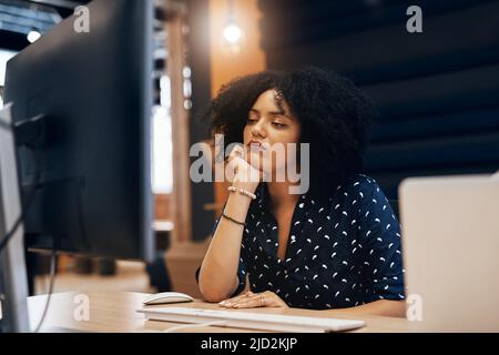 Iniziare a perdere la mia attenzione. Scatto di una giovane stilista stanca in cerca di addormentarsi dietro il suo computer in ufficio durante il giorno. Foto Stock