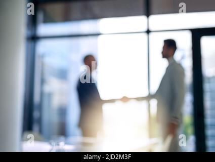 Creazione di relazioni commerciali. Scatto sfocato di due uomini d'affari che scuotono le mani in un ufficio moderno. Foto Stock