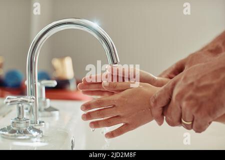 Proprio come ti ha mostrato papà. Scatto corto di un padre non identificabile che mostra alla sua bambina come lavarsi le mani. Foto Stock