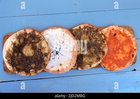 Un insieme di maouajanet libanese o manaqish, zaatar, formaggio, e lahm b ajin. Foto Stock