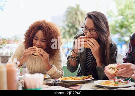 Questo è il posto migliore in città. Scatto corto di un amico che mangia hamburger all'aperto. Foto Stock