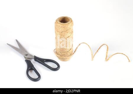 Treccia di spago di iuta naturale e forbici isolate su sfondo bianco Foto Stock