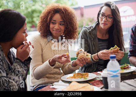 Questo è il posto migliore in città. Scatto corto di un amico che mangia hamburger all'aperto. Foto Stock