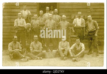 Cartolina originale del WW1 dei soldati sulle operazioni di pulizia fuori di una capanna, spazzole, mop, pala, bagno di stagno, secchio del fuoco, l'uomo ha mensa dell'esercito sulla cinghia. Forse l'equipaggio di fuoco. Alla loro caserma dell'esercito .U.K. Foto Stock