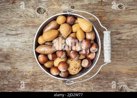 Secchio di stagno vecchio con assortimento di dadi in gusci. Vista dall'alto. Foto Stock