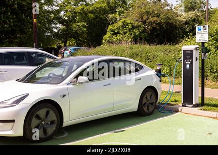 Woodbridge Suffolk UK Maggio 18 2022: Una Tesla Model 3 per la ricarica di auto elettriche presso la stazione di ricarica plug-in in un parcheggio pubblico a Suffolk, Regno Unito Foto Stock