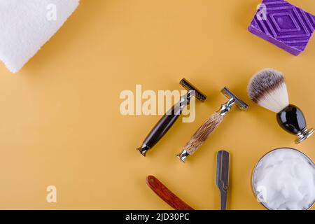 Diversi vecchi rasoi vintage, schiuma, asciugamani, e spazzola su uno sfondo giallo. Vista dall'alto spazio per tex Foto Stock