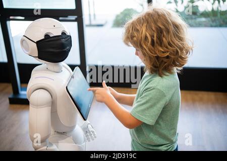 il bambino occupato interagisce con l'intelligenza artificiale del robot, la comunicazione Foto Stock