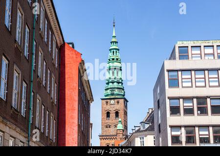 La vecchia torre e la guglia del Nikolaj Contemporary Art Center (Kunsthallen Nikolaj) visti attraverso edifici più moderni a Copenhagen, Danimarca Foto Stock