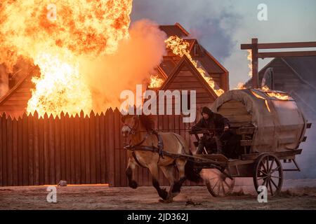 Ralswiek, Germania. 16th giugno 2022. Un cocchiere guida una carrozza bruciante di fronte alla silhouette bruciante della città di Bergen in una scena del Festival Störtebeker. Per molto tempo era tranquilla di fronte al panorama del Mar Baltico della scena naturale Ralswiek sull'isola di Rügen. Ora ritorna il Störtebeker Festival. Si tratta di amore, ma anche macchinazioni scure gettano le loro ombre. Il gioco "in the Face of the Wolf" con i leggendari pirati Klaus Störtebeker e Goedeke Michels ha la sua prima sull'isola di Rügen su 18. 06,2022. Credit: Stefan Sauer/dpa/Alamy Live News Foto Stock