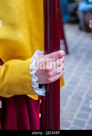 Una mano di fratello che tiene una bandiera durante la settimana Santa a Úbeda. Foto Stock