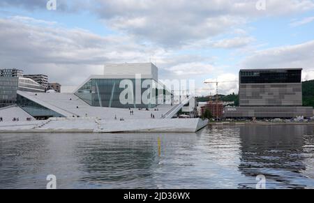 Oslo, Norvegia. 08th giugno 2022. Il teatro dell'opera nella città portuale di Bjørvika, sede dell'Opera di Stato Norvegese (l). Il tetto è accessibile. Sulla destra, il nuovo edificio del Museo del Munch. Credit: Kathrin Deckart/dpa/Alamy Live News Foto Stock