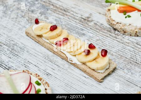Croccanti con formaggio cremoso e frutta su sfondo bianco di legno Foto Stock