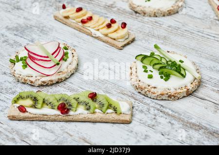 Torta di riso e croccanti con formaggio cremoso e verdure su tavola di legno Foto Stock