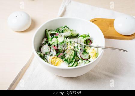 Insalata di primavera con cetriolo, ravanello e uova serviti in un recipiente di ceramica. Foto Stock