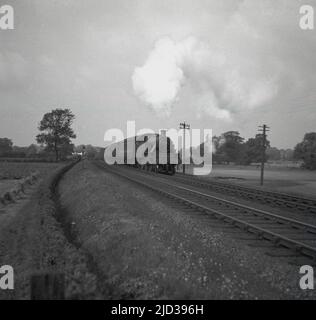 1950s, Historical, una locomotiva a vapore (138) che viaggia lungo una linea ferroviaria, vicino a Bramhall, Stockport, Manchester, Inghilterra, REGNO UNITO. Foto Stock