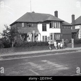 1950s, storico, quattro bambini piccoli sul marciapiede fuori di una grande casa a Woodford Road, Bramhall, una prospera area suburbana a sud di Stockport, Manchester, Inghilterra, Regno Unito. Foto Stock