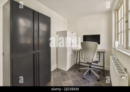 Ampia e luminosa camera a mansarda per il lavoro e il relax, dotata di armadio nero e radiatore Foto Stock