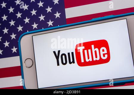 Kumamoto, GIAPPONE - Feb 22 2022 : l'immagine concettuale del logo di YouTube su un iPhone su sfondo di una bandiera americana. Foto Stock