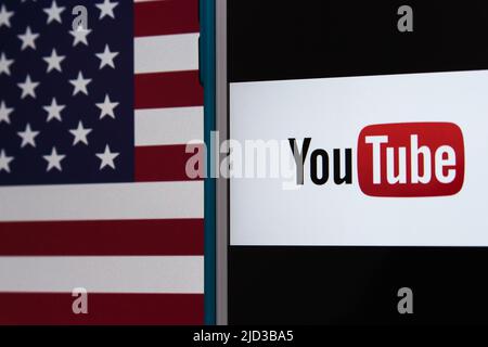 Kumamoto, GIAPPONE - Feb 22 2022 : l'immagine concettuale del logo di YouTube su un iPhone su sfondo di una bandiera americana. Foto Stock