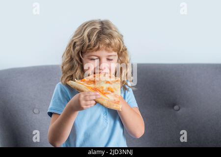 Un bambino felice cotta fuori una fetta grande di pizza fresca fatta. Ragazzino che mangia la pizza. Il ragazzo piccolo carino mangia le pizze. Felice bel ragazzo giovane adolescente che tiene fetta Foto Stock