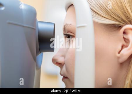 Una giovane ragazza alla reception dell'oftalmologo controlla la vista su un apparecchio speciale. Primo piano. Foto Stock