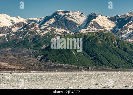 Dischantment Bay, Alaska, USA - 21 luglio 2011: Paesaggio con ghiacci galleggianti di fronte a una catena montuosa parzialmente boschiva con cime innevate un Foto Stock