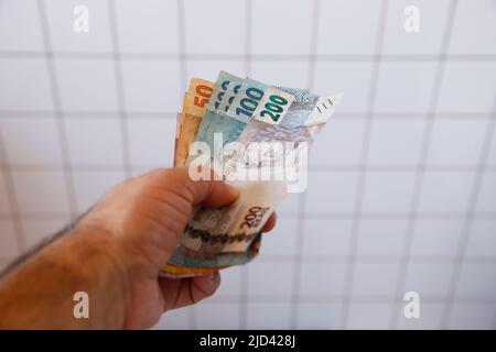 mano in possesso di diverse banconote del brasile - banconote reali brasiliane - effettuare il pagamento Foto Stock