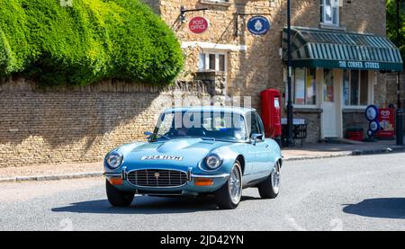 1972 Blue e TYPE Jaguar guida attraverso un villaggio inglese Foto Stock