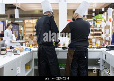 Due Chef visti da dietro: Servire i clienti dietro il loro tavolo. Foto Stock