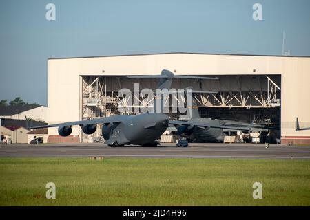Due Boeing C-17 Globemasters parcheggiati presso la base dell'aeronautica militare di Charleston con uno parcheggiato in un hangar di manutenzione Foto Stock
