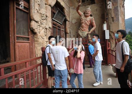 Tianshui, provincia cinese di Gansu. 9th giugno 2022. I turisti visitano le Grotte di Maijishan nella città di Tianshui, nella provincia di Gansu della Cina nord-occidentale, il 9 giugno 2022. Le grotte di Maijishan, che hanno più di 1.600 anni, sono scolpite nelle grotte di un'isolata vetta montana sull'antica Via della Seta nella città di Tianshui. Credit: Chen Bin/Xinhua/Alamy Live News Foto Stock